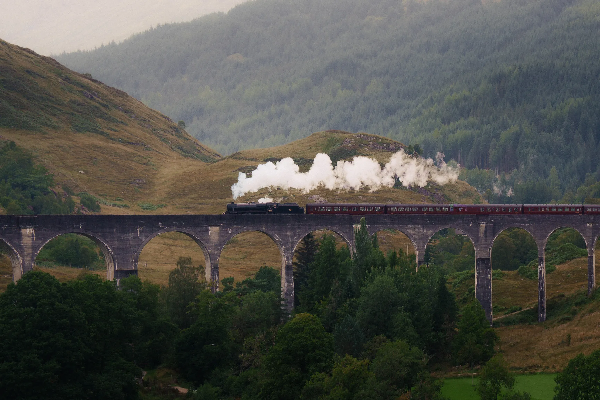 El tren de vapor Jacobite sobre el viaducto de Glenfinnan, con la estela de vapor sobre los arcos. Highlands de Escocia.