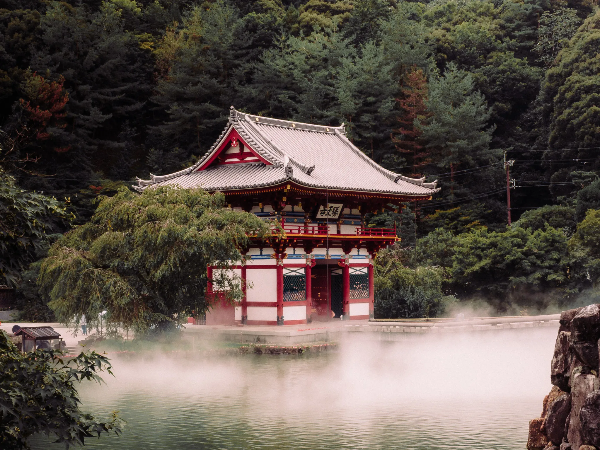 Pabellón sobre el estanque envuelto en neblina, con el bosque de fondo. Templo Katsuō-ji, Osaka.